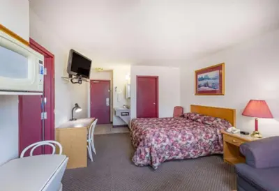 a hotel room with a bed and a bathroom at Almada Inn in Fort Nelson