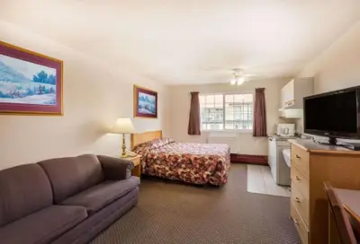 a living room with a couch and a bed at Almada Inn in Fort Nelson
