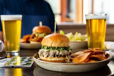 a sandwich and fries on a table with two beers at Headwaters Lodge at Eagle Ranch Resort in Invermere