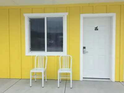 two chairs sitting outside of a house with a door at Humpback Inn in Port McNeill