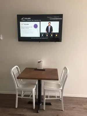 a table with two chairs and a tv on the wall at Humpback Inn in Port McNeill