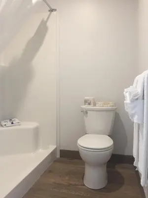 a white bathroom with a toilet and a bath tub at Humpback Inn in Port McNeill