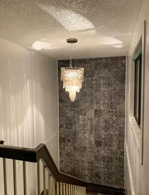 a staircase with a chandelier in a room with a wall at 7 Day's Hotel in Lamont