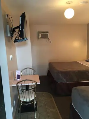 a room with a bed and a table and a chair at Ranchland Villa Motel in Merritt