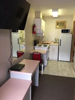 a small kitchen with white appliances and red chairs at Ranchland Villa Motel in Merritt