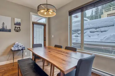 a dining room with a wooden table and chairs and a window at Echo Landing#02 By Bear Country in Sun Peaks