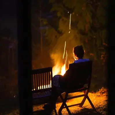 a person sitting on a bench in front of a fire at Maple Heart Ranch in Shawnigan Lake