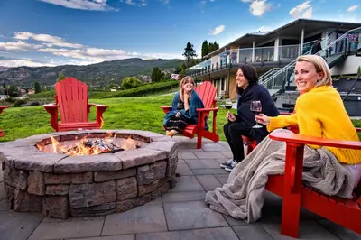 a group of women sitting around a fire pit at The Inn at Therapy Vineyards in Naramata
