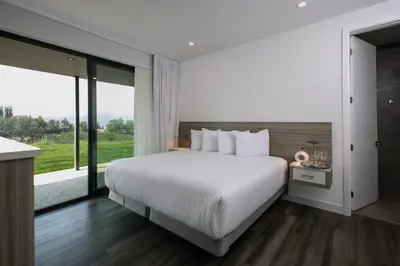 a bedroom with a white bed and a large window at The Inn at Therapy Vineyards in Naramata