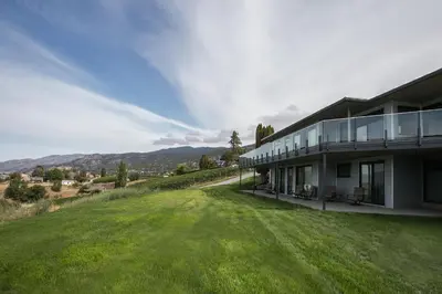 a house with a large yard next to a building at The Inn at Therapy Vineyards in Naramata