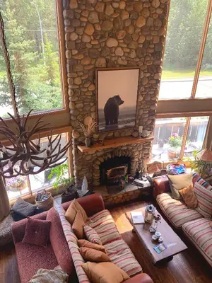 a living room with a stone fireplace with a bear on the television at Ambleside Lodge Bed & Breakfast in Canmore