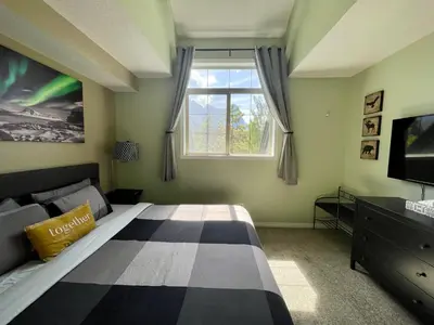 a bedroom with a large bed and a window at Renovated Chalet at Mystic Springs, Mountain Views, Pets Welcome! in Canmore