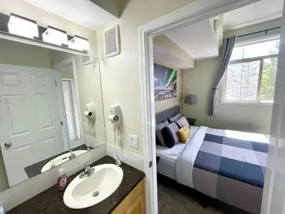 a bathroom with a bed and a sink and a mirror at Renovated Chalet at Mystic Springs, Mountain Views, Pets Welcome! in Canmore