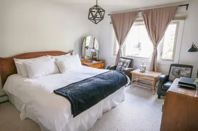a bedroom with a bed and a chair and a mirror at North House - Banff Mountain Home- The Real Rockies Experience in Banff