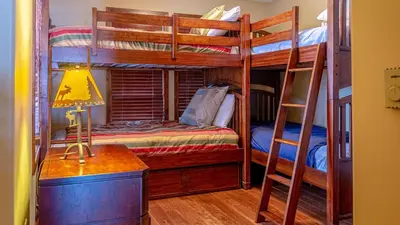 a bedroom with bunk beds with a desk and a lamp at Woodhaven #11 by Bear Country in Sun Peaks