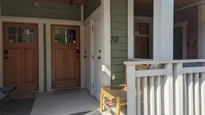 a porch of a house with two doors and a bench at Settlers Crossing #70 by Bear Country in Sun Peaks
