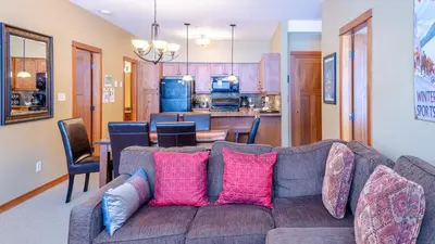 a living room with a couch with pink pillows at Settlers Crossing #61 by Bear Country in Sun Peaks