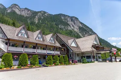 a large building with trees in front of a mountain at Peaks Lodge in Revelstoke