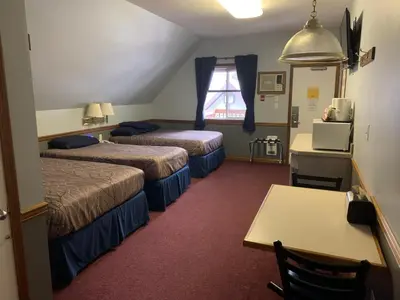 a hotel room with two beds and a table at Peaks Lodge in Revelstoke