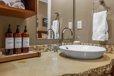 a bathroom sink with bottles of wine on a counter at Sophisticated MTN 2 Bedroom Pool Hot Tub managed by Little Sister Getaways in Canmore