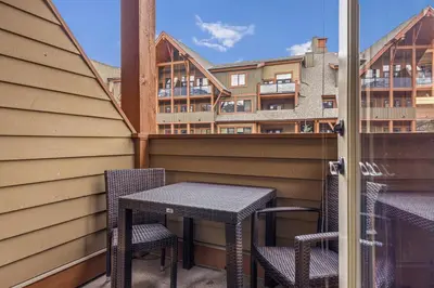 a balcony with two tables and chairs and a building at Sophisticated MTN 2 Bedroom Pool Hot Tub managed by Little Sister Getaways in Canmore