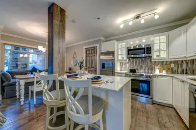 a kitchen with white cabinets and a island with bar stools at Sunpath Retreat- Convenience Meets Comfort & Style in Whistler