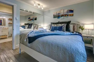 a bedroom with a large bed and a mirror at Sunpath Retreat- Convenience Meets Comfort & Style in Whistler