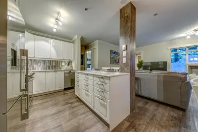 a large kitchen with white cabinets and a sink at Sunpath Retreat- Convenience Meets Comfort & Style in Whistler