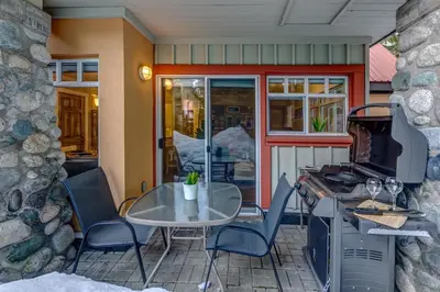a patio with a table and chairs and a stove at Sunpath Retreat- Convenience Meets Comfort & Style in Whistler
