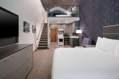 a bedroom with a bed and a kitchen with a staircase at Best Western Plus Prince George in Prince George