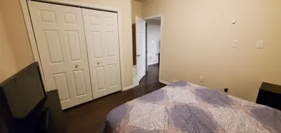 an empty room with a bed and white doors at Parson Creek Retreat in Fort McMurray
