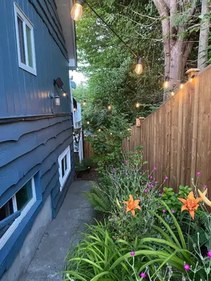 a garden with flowers and a fence with lights at The Wayward Inn in Chemainus
