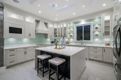 a kitchen with white cabinets and a large island with stools at Sun suite in Surrey