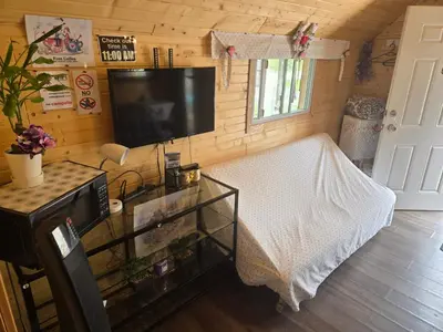 a room with a bed and a tv and a table at Blue River Campgrounds & Cabin-public washroom in Blue River