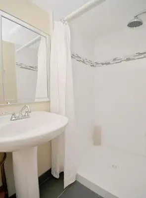 a white bathroom with a sink and a mirror at Heron View Cottage by EMR Vacation Rentals in Sidney