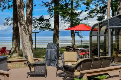 a group of chairs and tables on a patio near the beach at Kye Bay Beach House by EMR Vacation Rentals in Comox