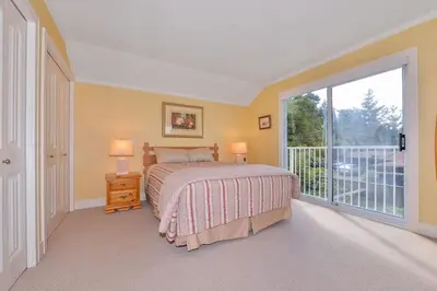 a bedroom with a bed and a large window at Kye Bay Beach House by EMR Vacation Rentals in Comox