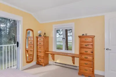 a bedroom with dressers and a window and a mirror at Kye Bay Beach House by EMR Vacation Rentals in Comox