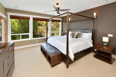 a bedroom with a canopy bed and windows at Nature's Gate Executive Estate by EMR Vacation Rentals in Victoria