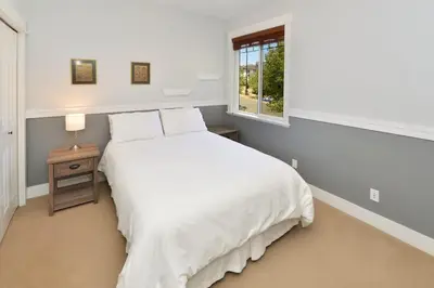 a white bedroom with a bed and a window at Nature's Gate Executive Estate by EMR Vacation Rentals in Victoria