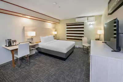 a hotel room with a bed and a desk and a tv at Quality Inn Sunshine Suites in Terrace