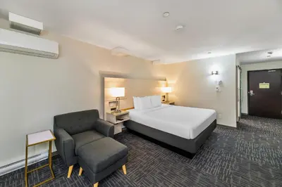 a hotel room with a bed and a chair at Quality Inn Sunshine Suites in Terrace