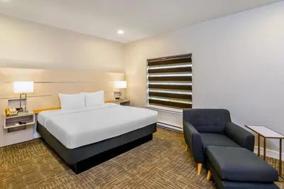 a hotel room with a bed and a chair at Quality Inn Sunshine Suites in Terrace