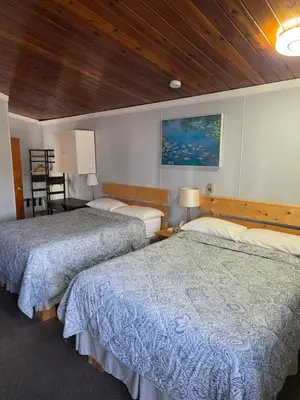 two beds in a hotel room with wooden ceilings at Bio Vista Motel in Wainwright
