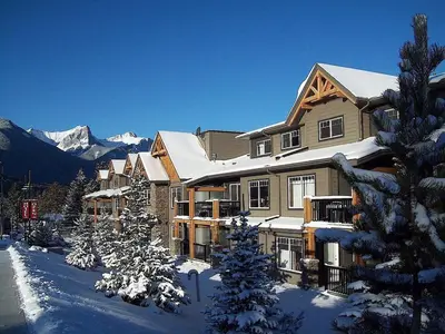 a large building in the snow with snow covered trees at Copperstone Resort in Dead Man's Flats