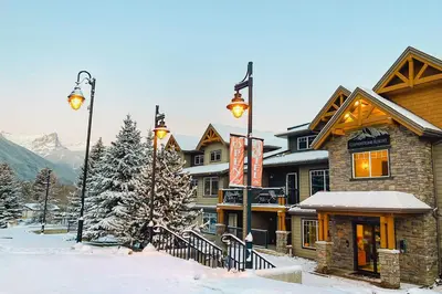 a building in the snow in front of a mountain at Copperstone Resort in Dead Man's Flats