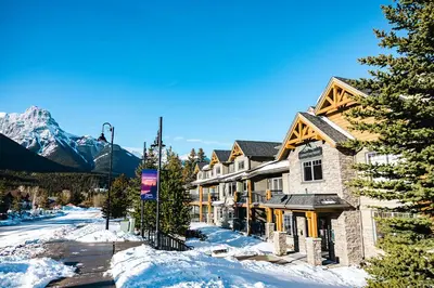 a house in the snow with mountains in the background at Copperstone Resort in Dead Man's Flats