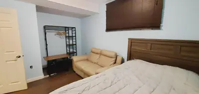 a bedroom with a bed and a chair next to a door at Parson Creek Cozy suite in Fort McMurray