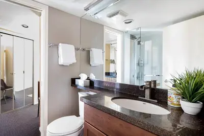 a bathroom with a sink and a toilet and a mirror at Mountain View Penthouse- 2BR Oasis at the Marquise in Whistler in Whistler