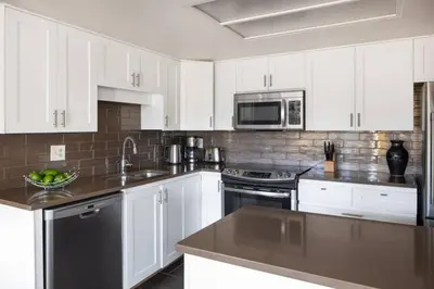 a kitchen with white cabinets and stainless steel appliances at Mountain View Penthouse- 2BR Oasis at the Marquise in Whistler in Whistler